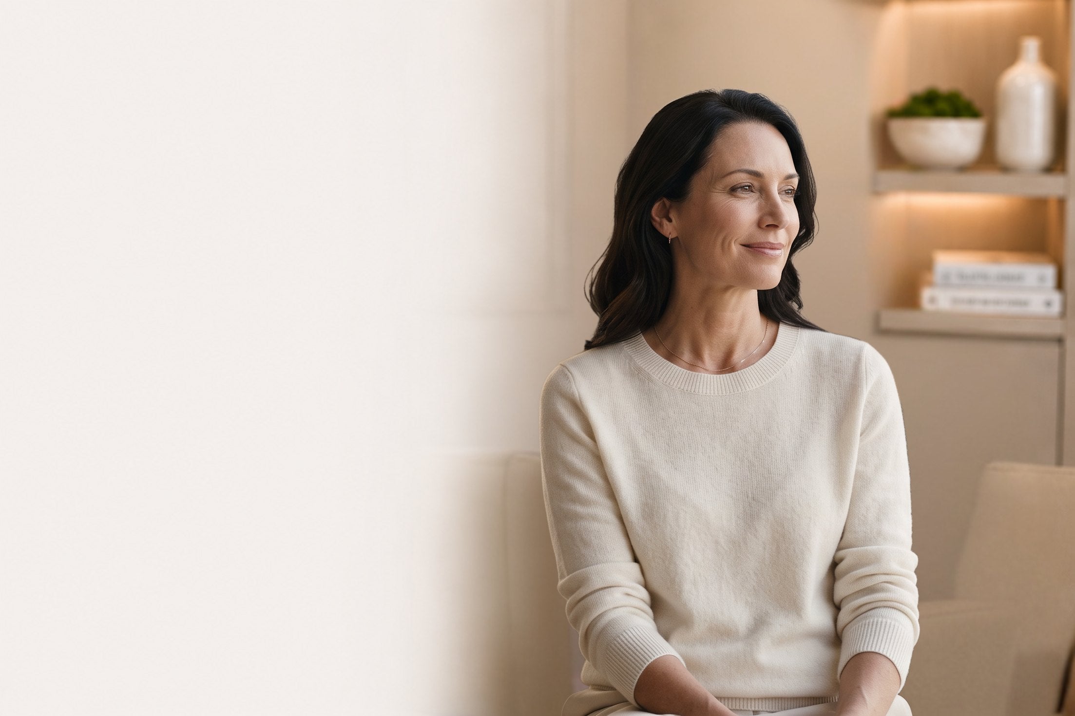 Smiling woman with dark hair in a crew-neck ivory sweater